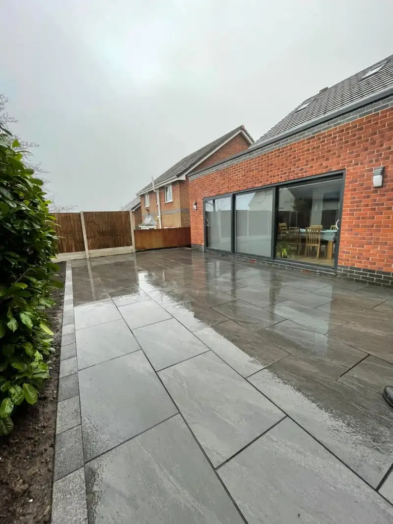Grey porcelain patio running the length of a brick extension with sliding doors
