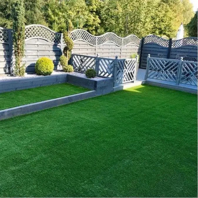 Artificial lawn edged by a grey rendered wall and trellis