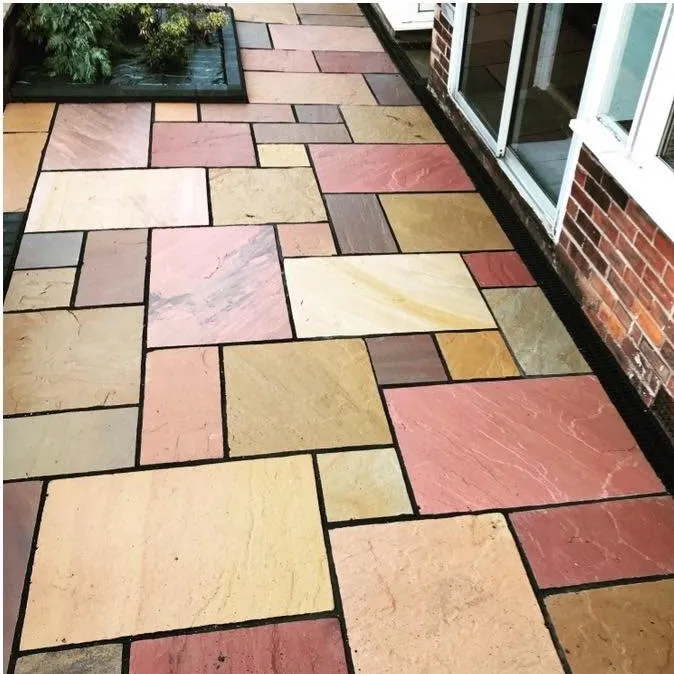 Multi-coloured sandstone patio beside a rendered house